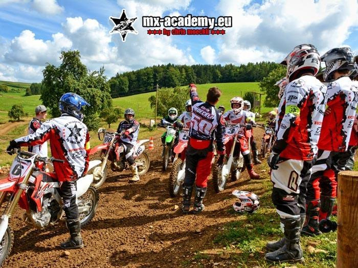 Youth motocross: a group of teenagers listens to the instruction while the motocross bikes stand ready