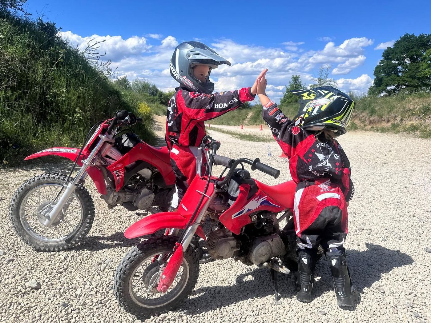 Motocross Kurs verschenken: zwei Kinder geben sich auf ihren Honda-Kinderbikes ein High Five