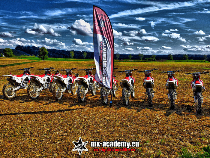 Motocross mieten: Mietmotorräder stehen in einer Reihe bereit, gleich daneben die Fahne